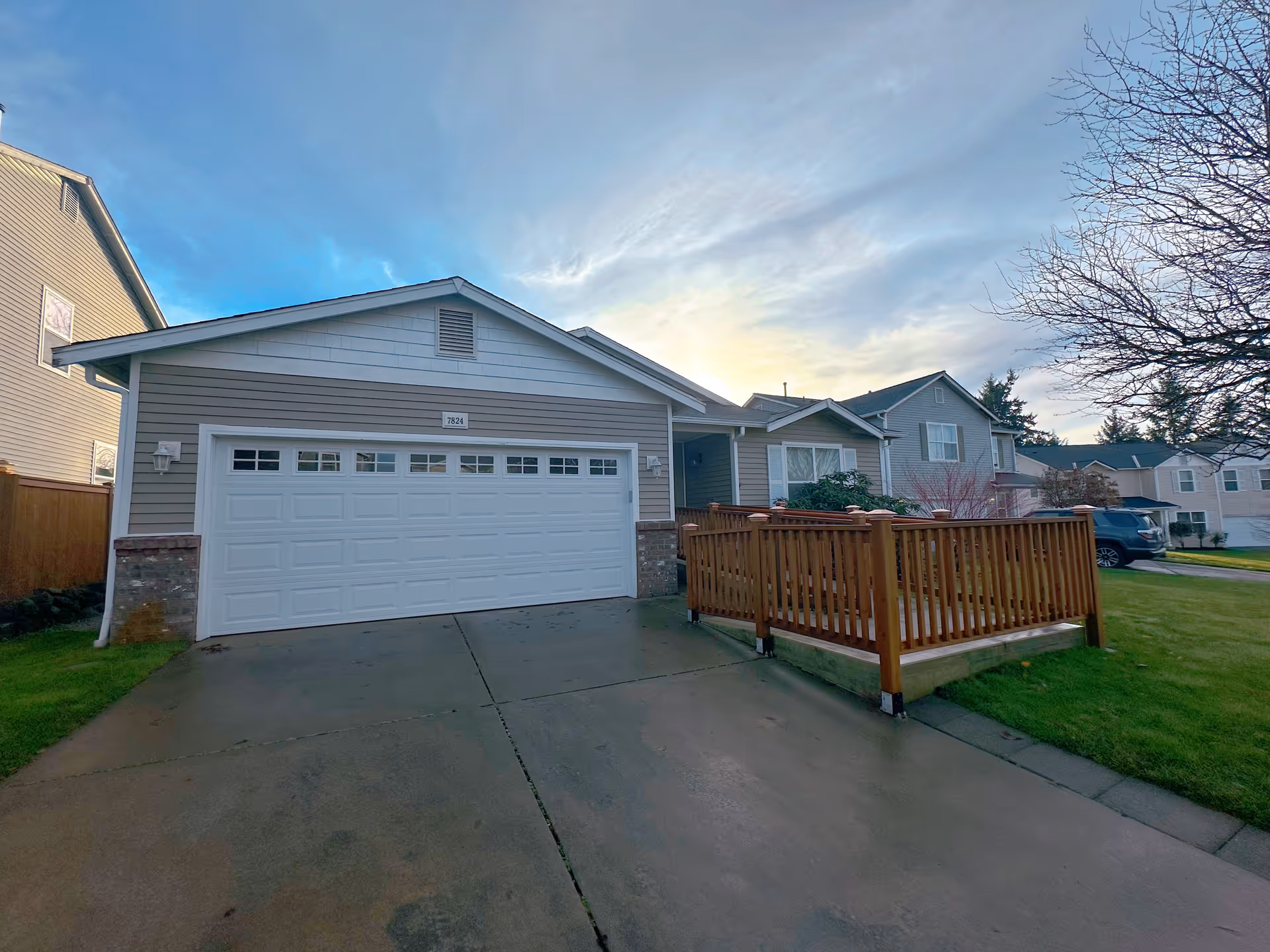 Suburban home with a two-car garage and wooden front deck.