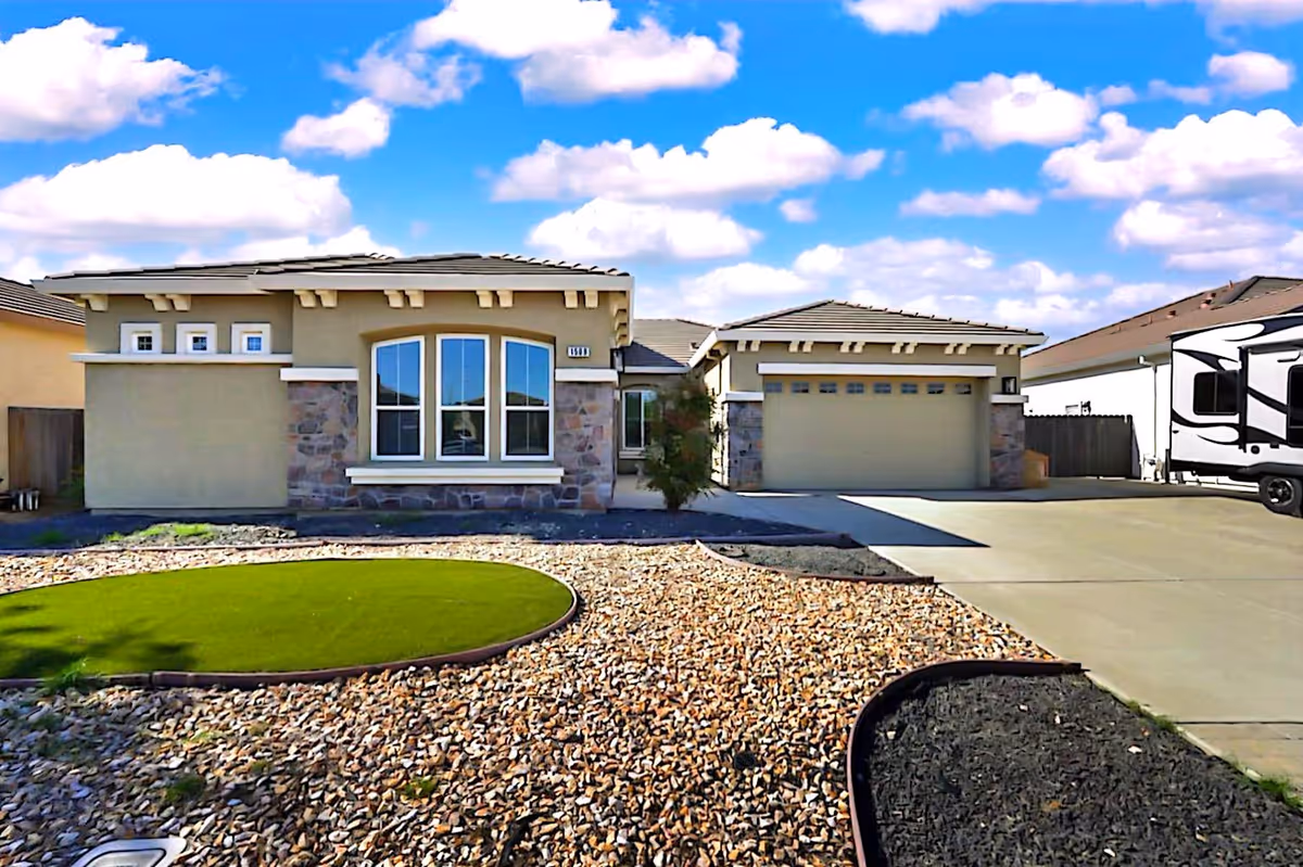 Front exterior view of Ansh Care Home, showing a two-car garage, RV trailer, and rocky landscaping.