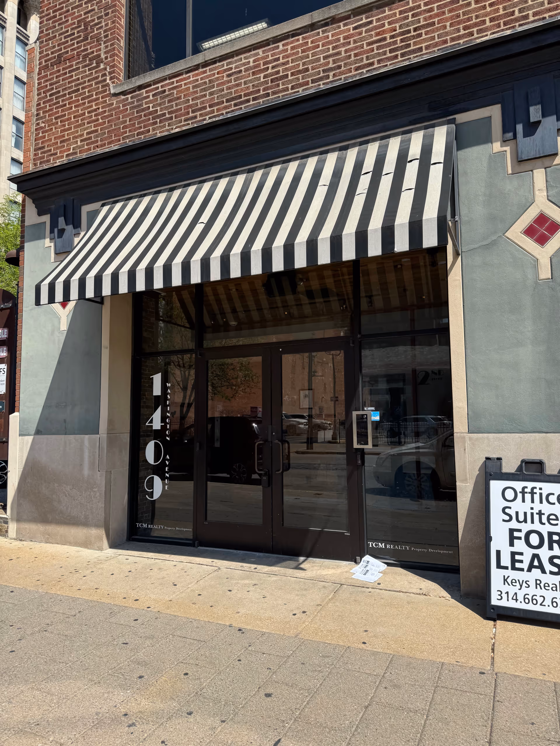 Storefront with a black-and-white striped awning over glass doors.