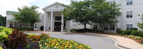 Front view of The Carillon senior living building with a curved driveway and landscaping.