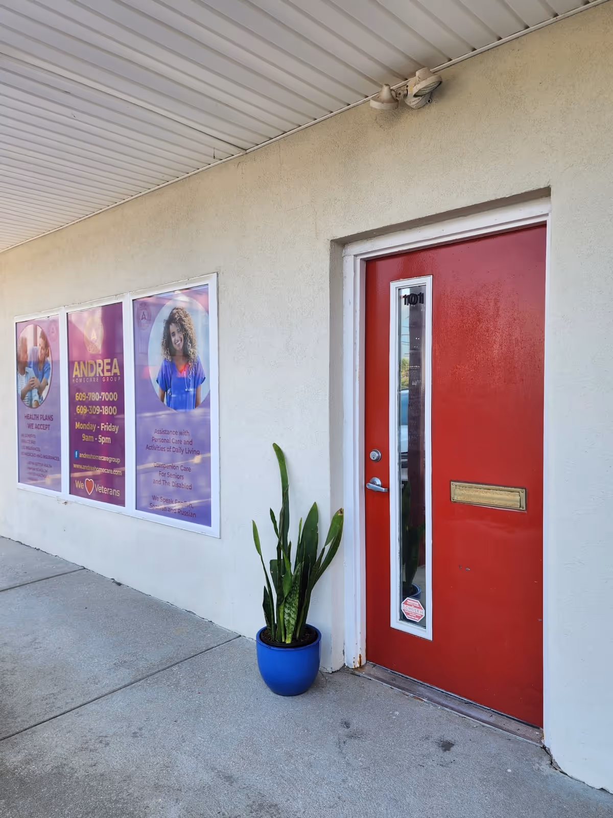 Red door entrance of a senior care facility with posters and a blue planter.