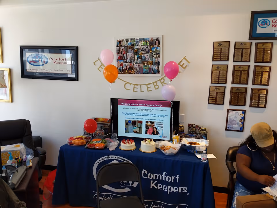 Indoor celebration at a Santa Monica senior facility with cake, balloons, and a photo collage.