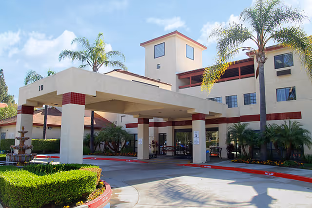 Exterior view of Brookdale Irvine entrance with a porte-cochere and palm trees.