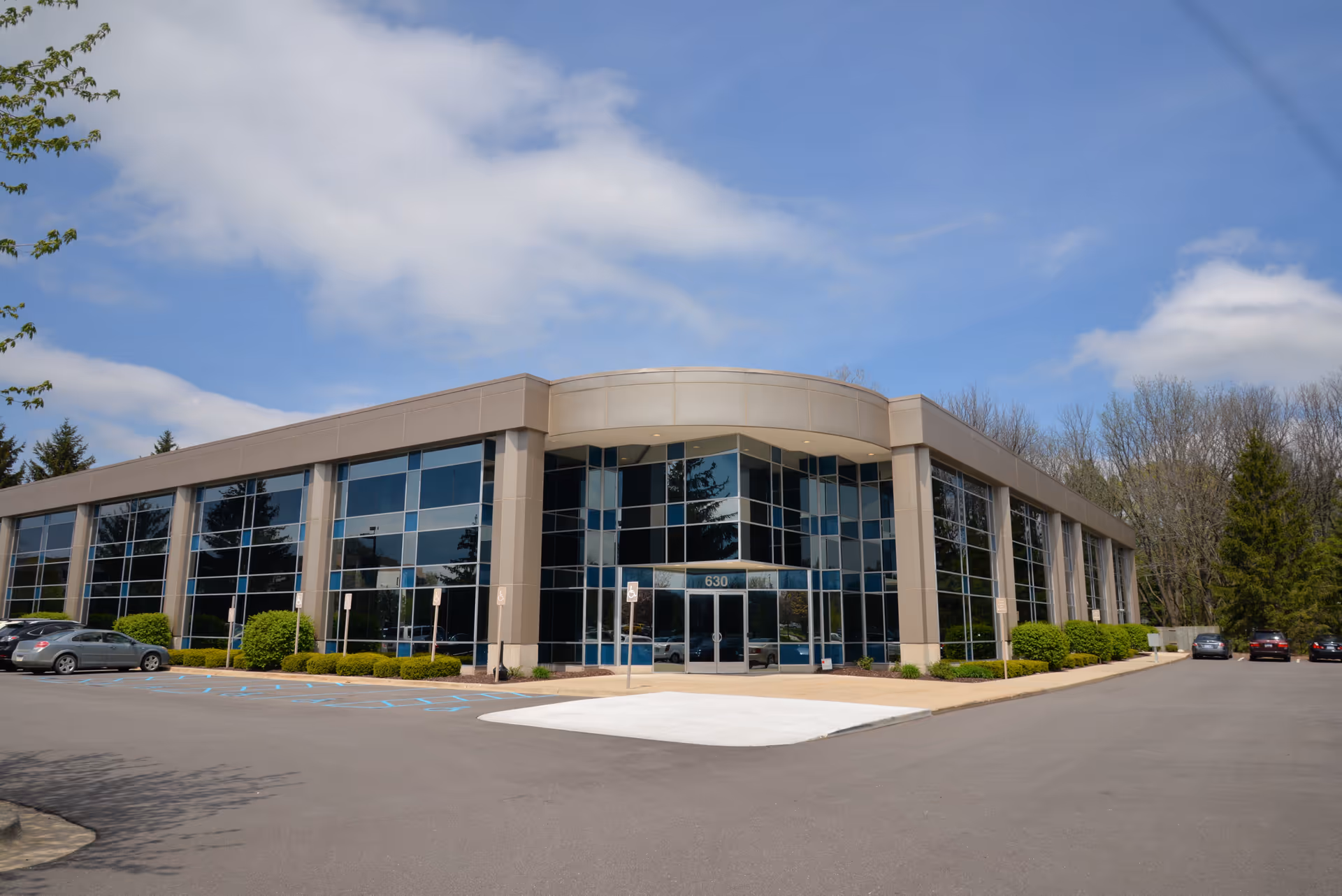 Exterior view of a modern glass-front senior living facility with a curved entrance.