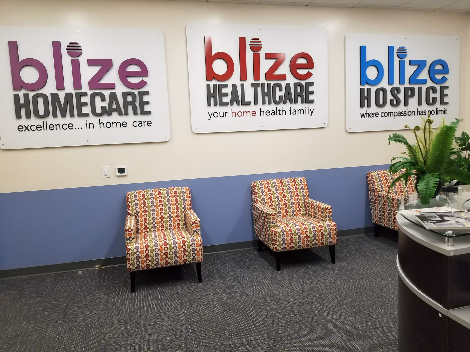 Lobby area with three patterned chairs and three blize signs on the wall.