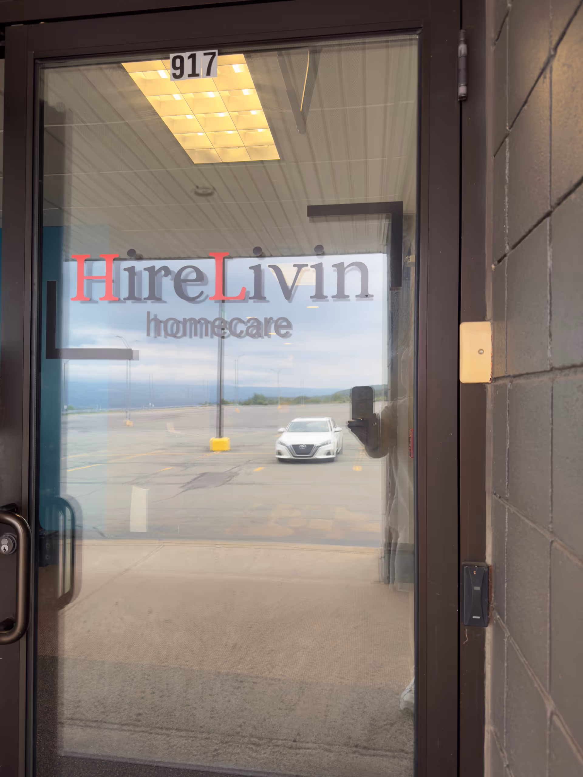 Glass door entrance displays HireLivin Homecare LLC signage with a parking lot reflection.
