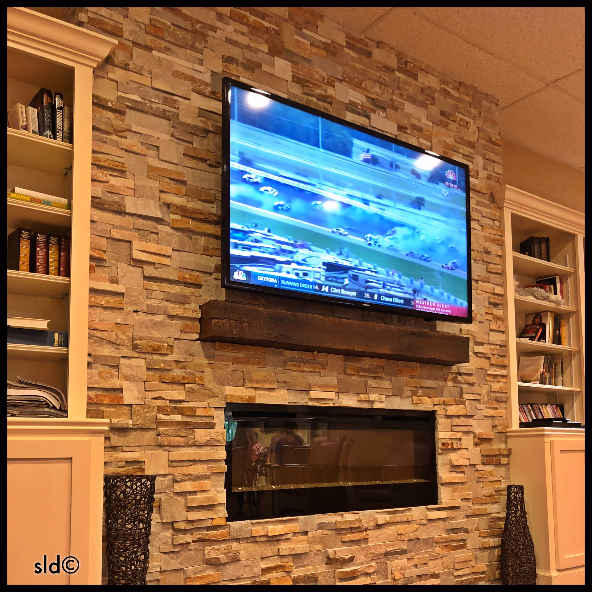 Stone fireplace with mounted TV and built-in bookcases in a warm living area.