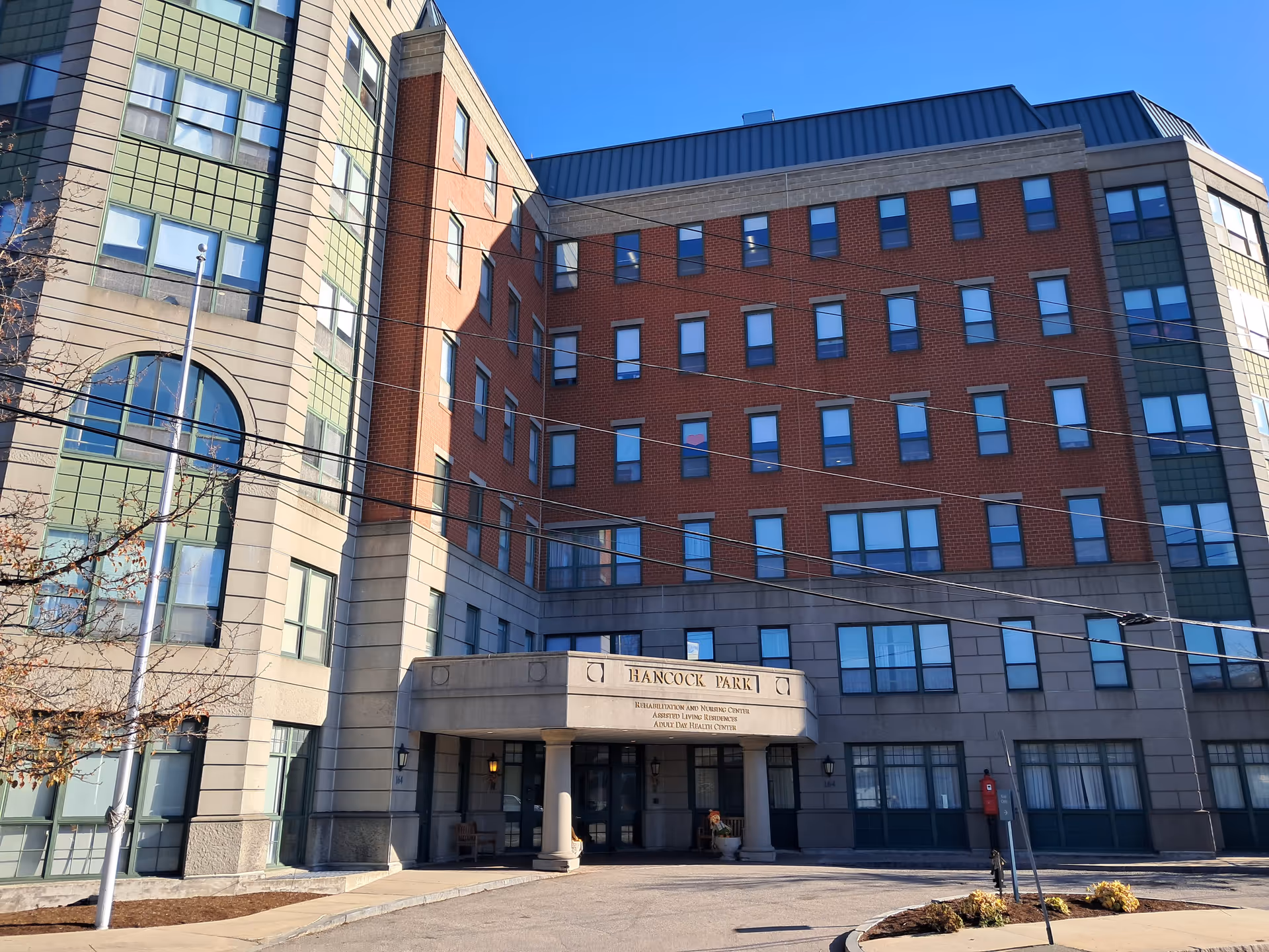 Exterior view of Assisted Living Residences at Hancock Park, brick and green-panel facade.