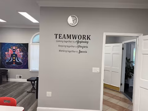 Interior common area with teamwork quote wall, clock, artwork, and seating.