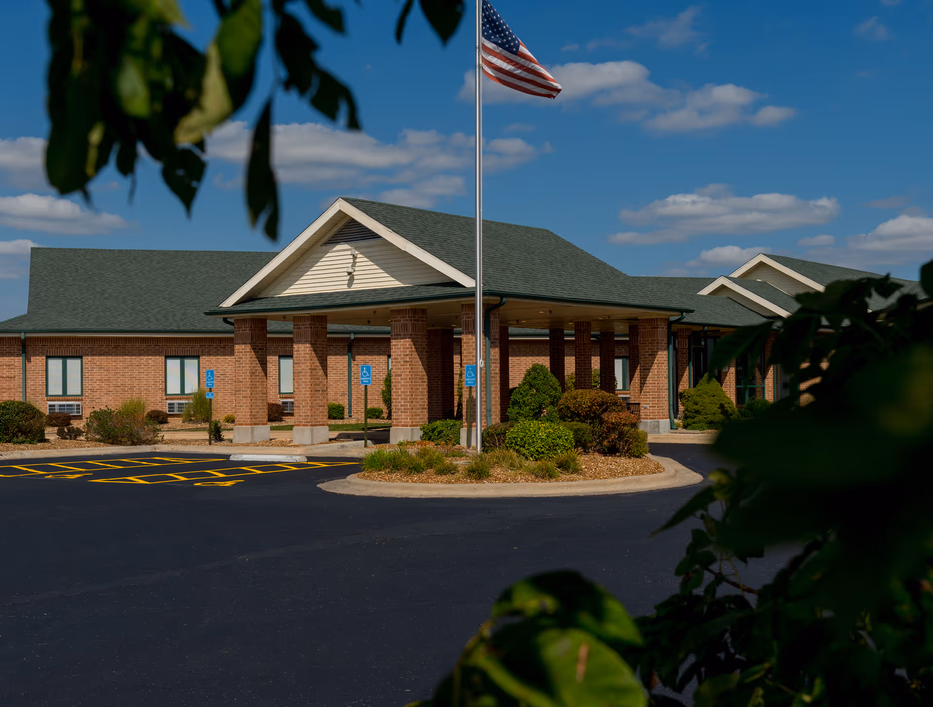 Exterior view of The Living Center with brick entrance and flag.