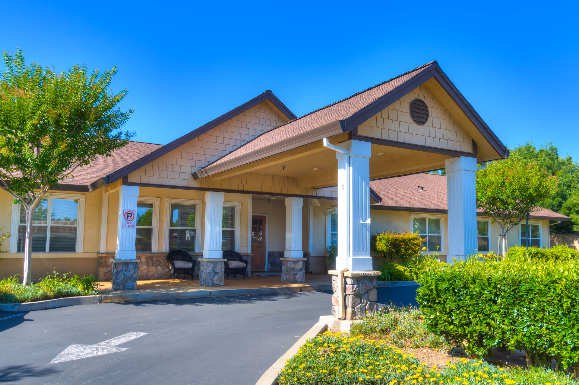 Exterior view of The Meadows Senior Living entrance with columns and manicured landscaping.