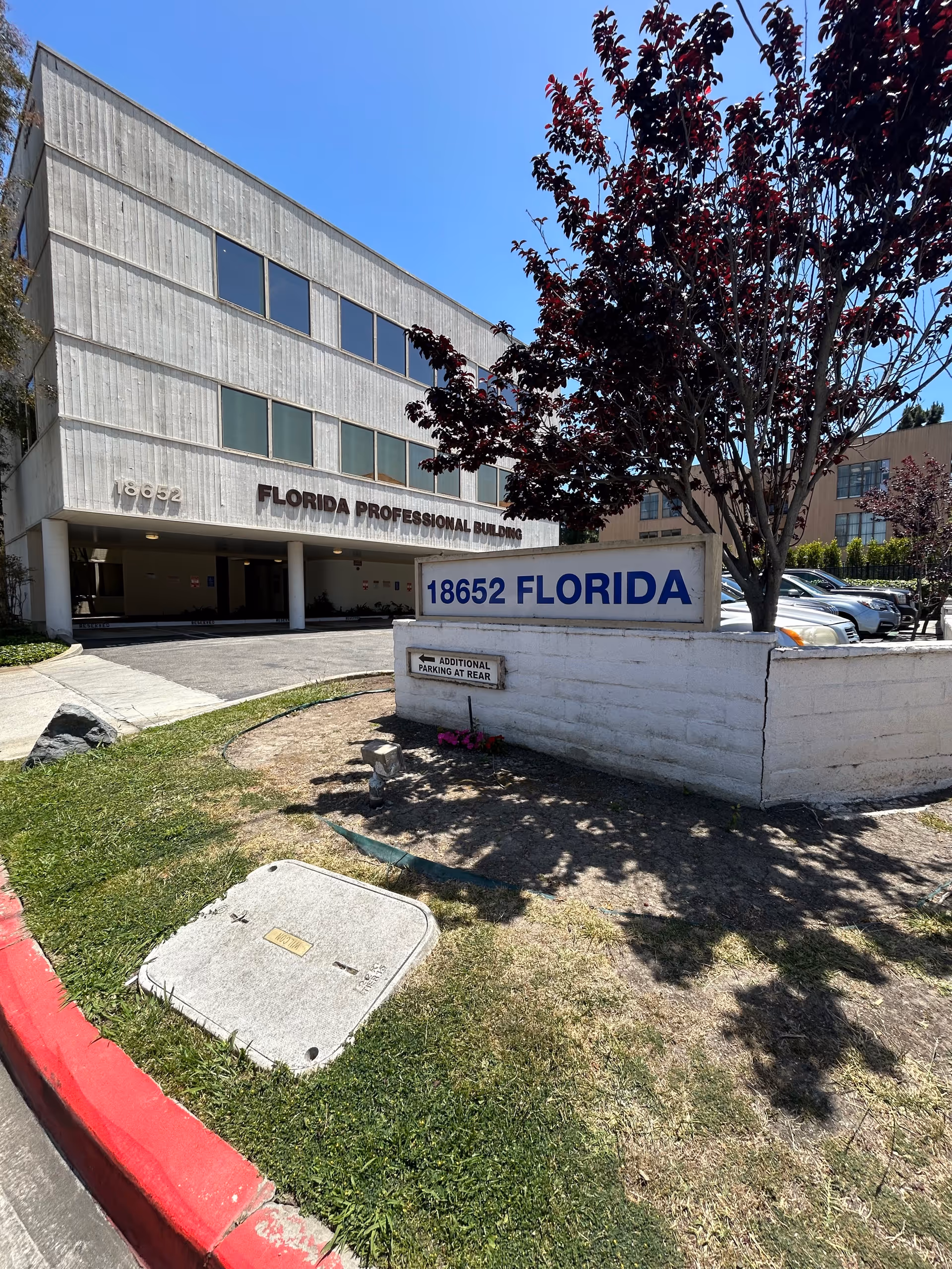 Exterior view of a concrete building with a blue 18652 FLORIDA sign and trees.