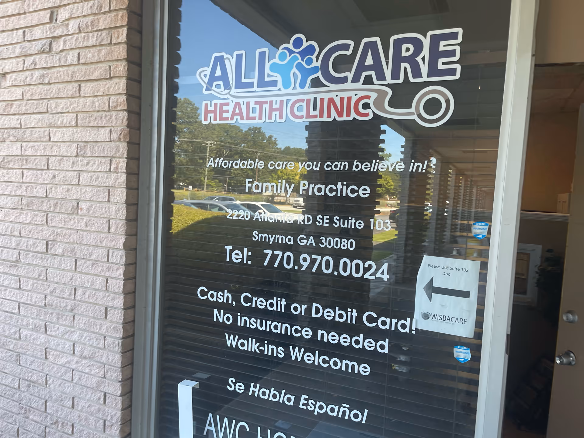 Glass entrance door displaying AllCare Health Clinic branding and contact information.
