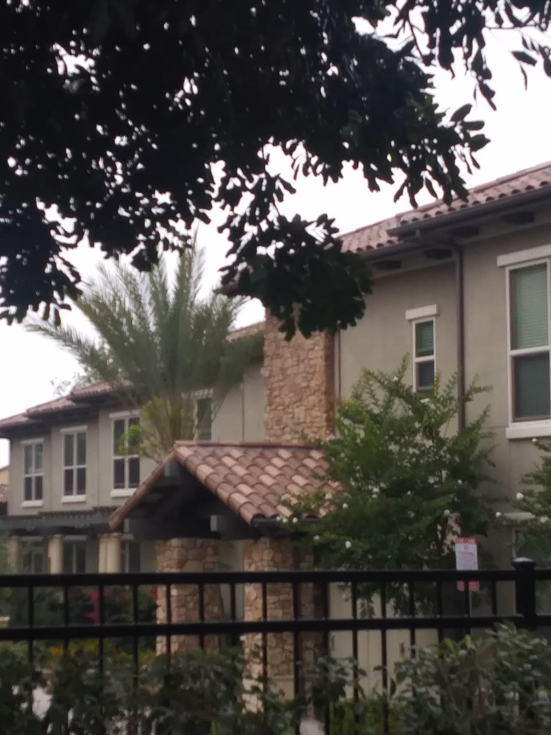 Exterior view of Villagio at Capriana Memory Care Community with stone columns and tile roof.