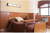 A small shared bedroom in Highland Care Center with two beds and a central table.