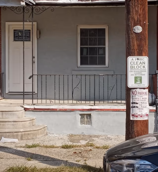Front porch view of a small house with a white door, window, and railing.