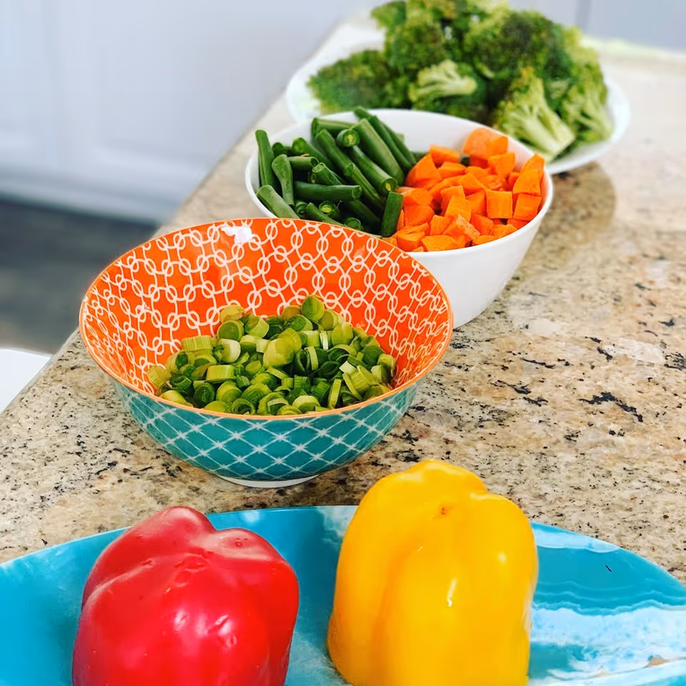 Colorful chopped vegetables in bowls on a granite kitchen counter, ready for meal prep.
