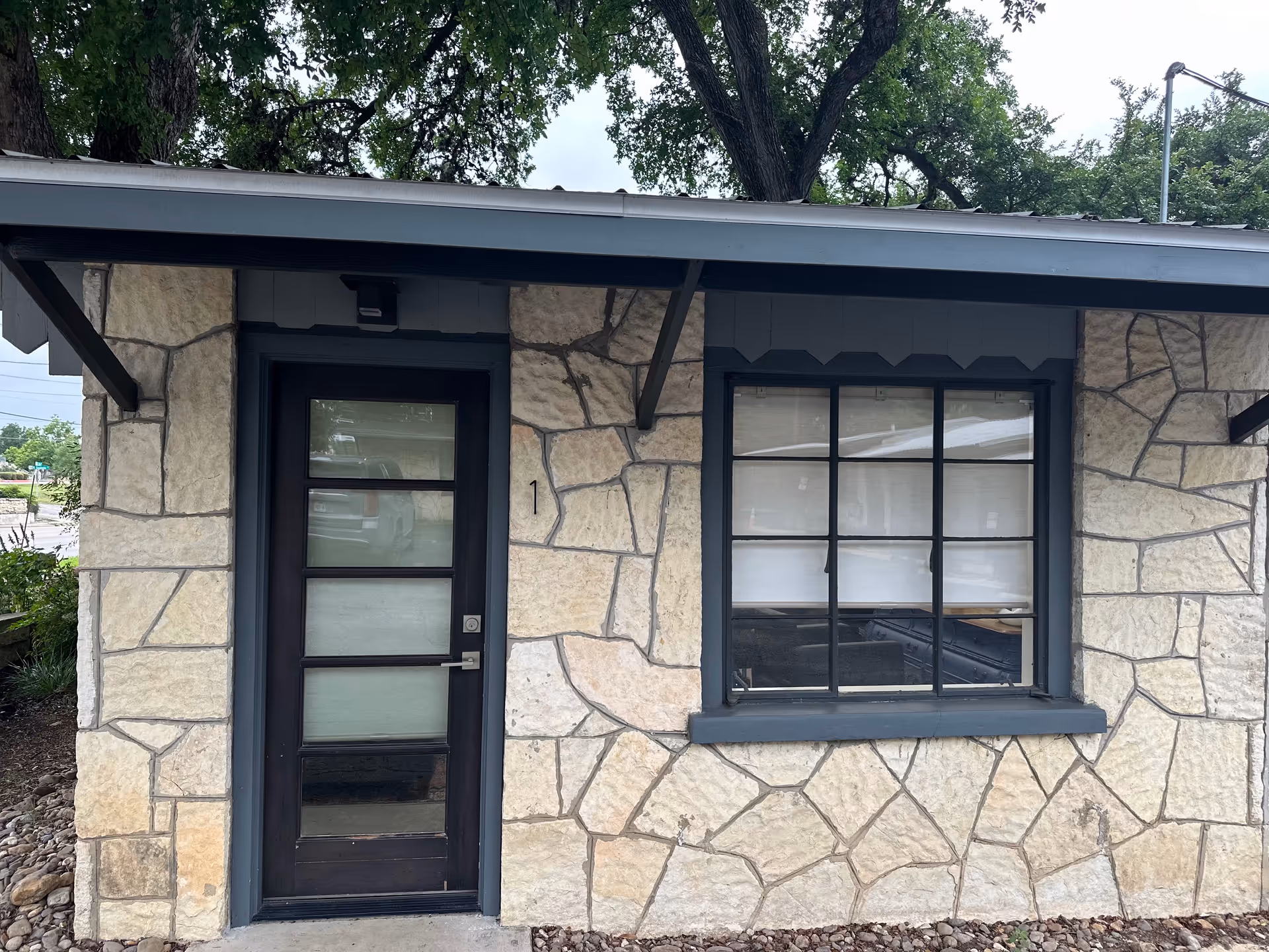 Stone-faced building exterior featuring a black door and a large window.