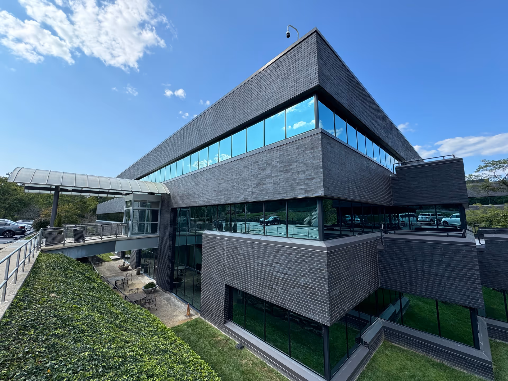 Modern dark brick senior living facility exterior with glass windows and blue sky.