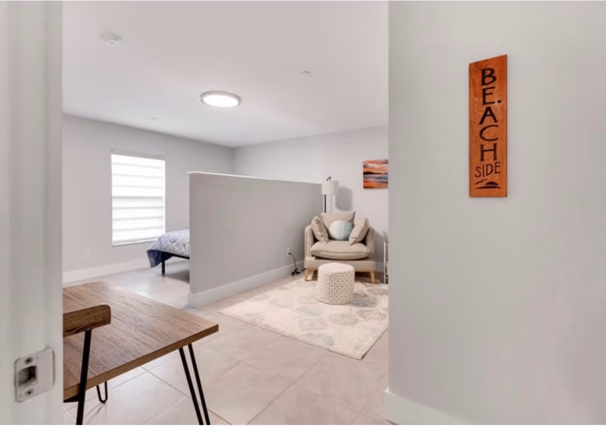 Bright interior living area with a partition, chair, rug, and a beach-themed sign