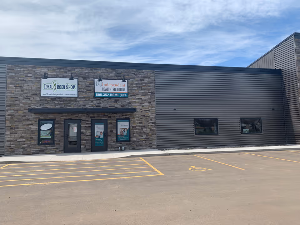 Exterior of a commercial building with stone facade and two storefront signs.