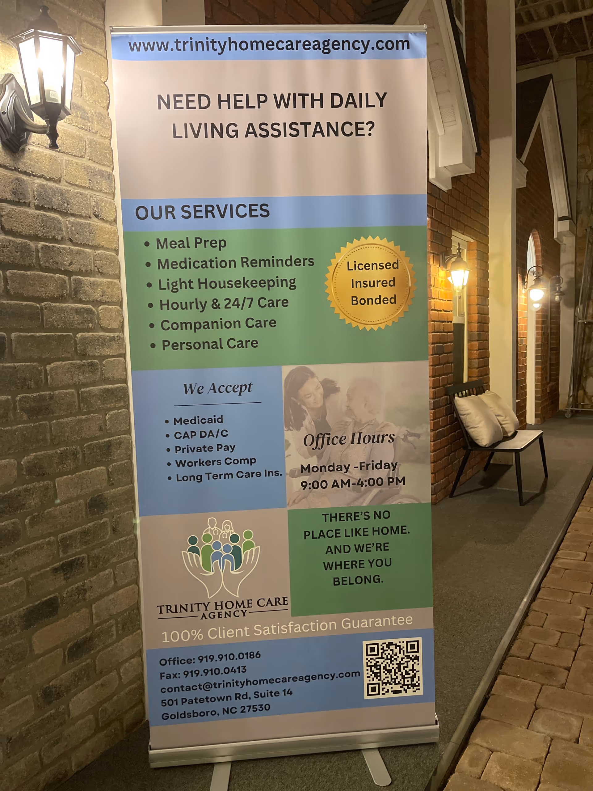 Vertical banner for Trinity Home Care Agency displayed in a brick interior hallway.