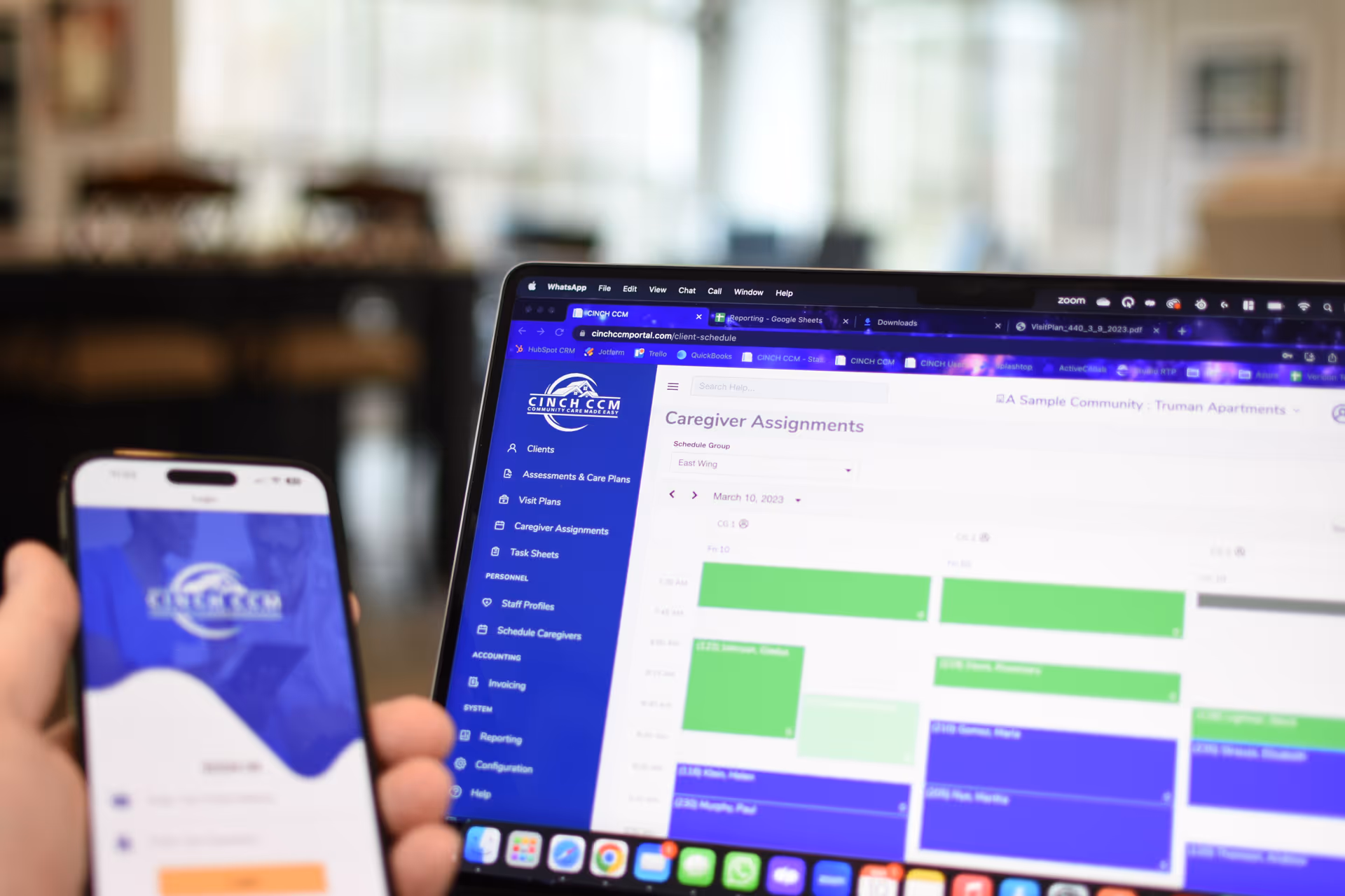 Laptop and phone screen show caregiver scheduling software in a facility.