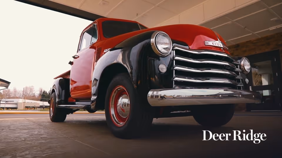 Red vintage truck parked under a facility canopy with Deer Ridge branding.