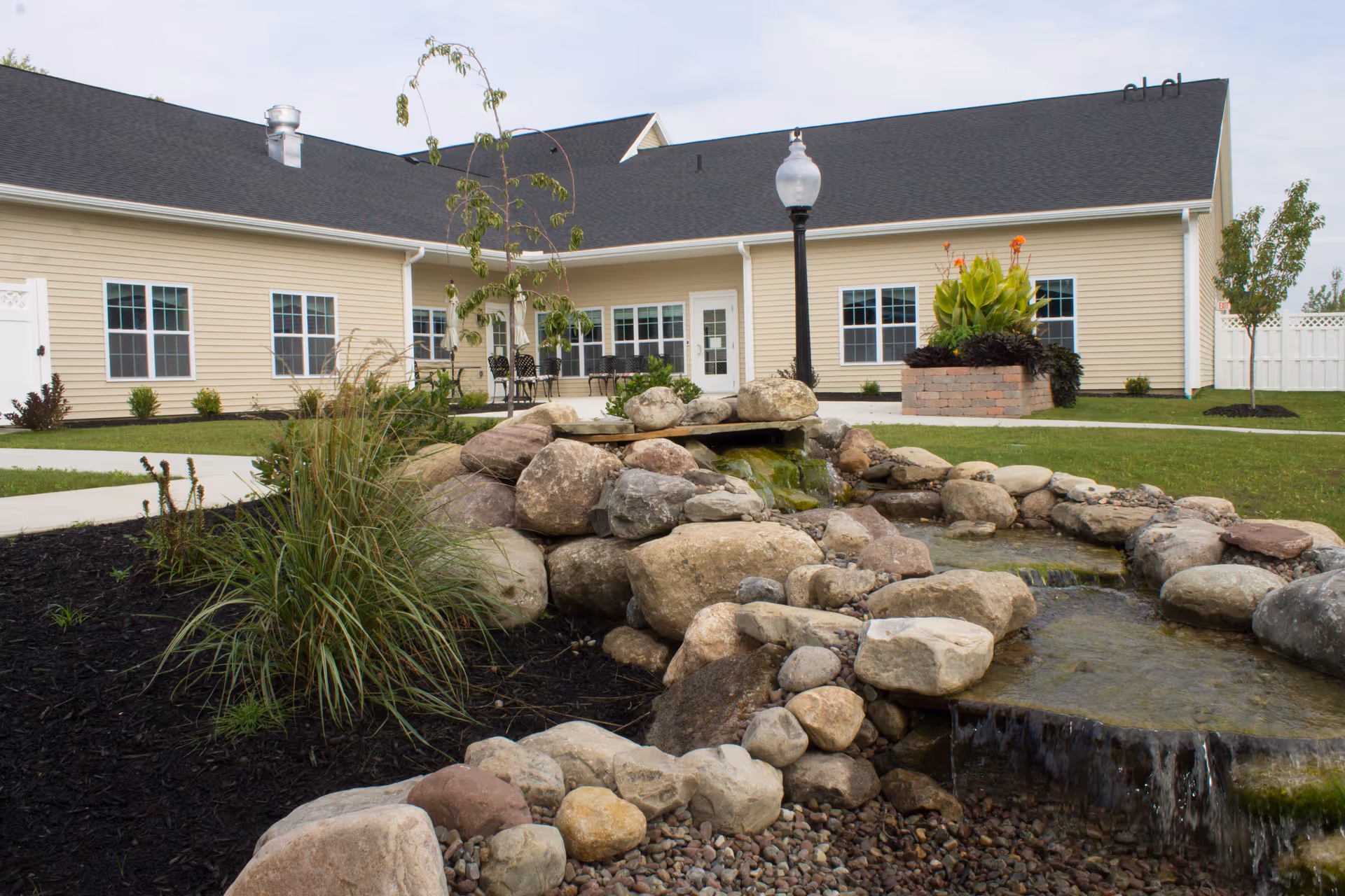 Exterior view of Rochester Presbyterian Home Creekstone with landscaped rocks and a water feature.