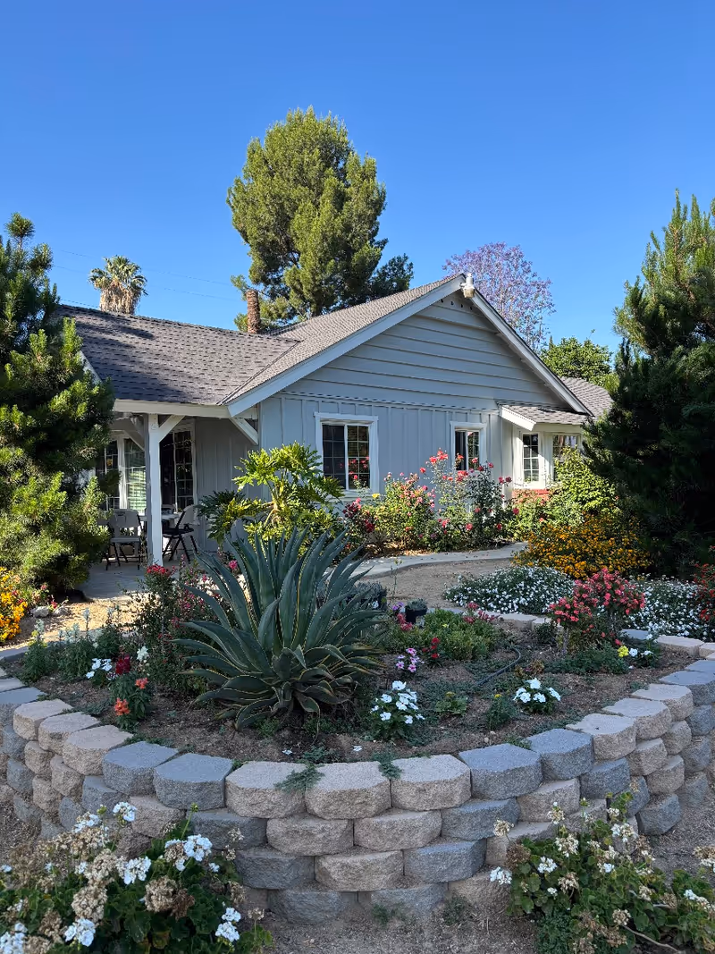 A single-story senior living facility with a gray exterior and landscaped front garden.
