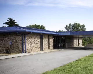 Exterior view of a brick facility with a blue canopy and glass entrance.