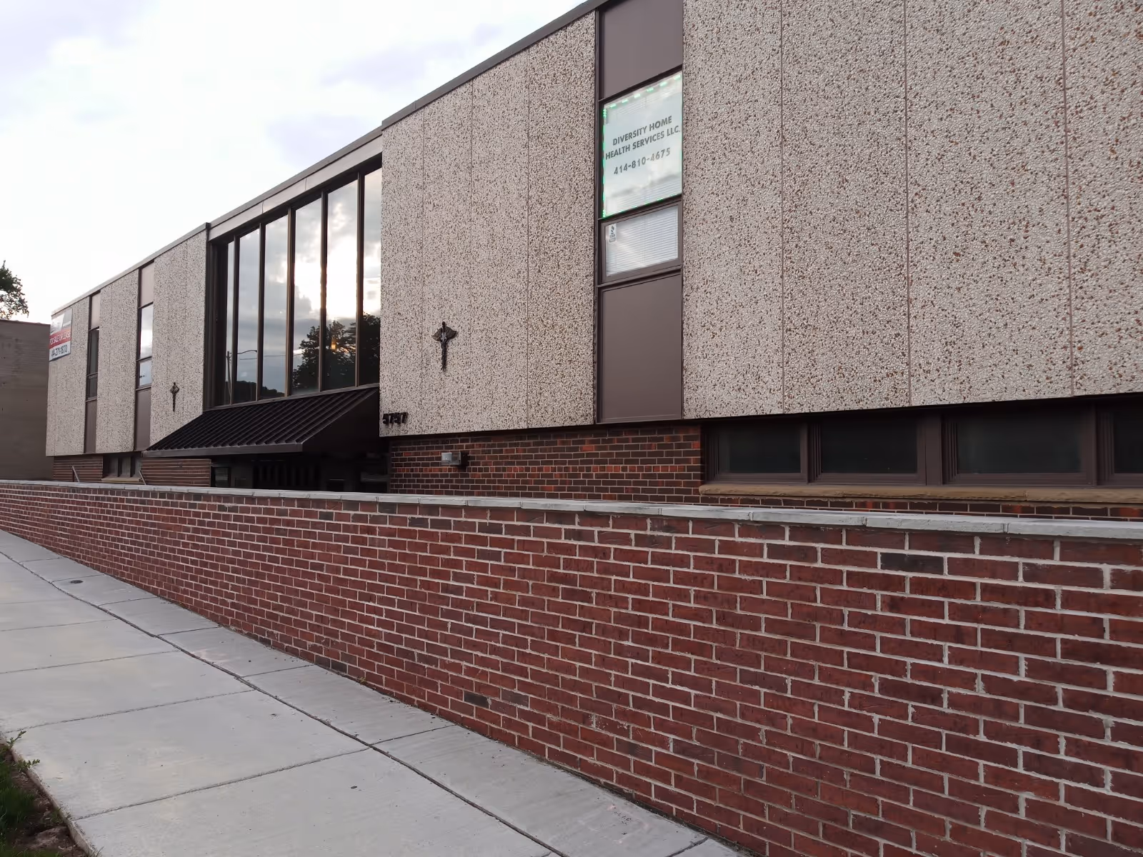 Exterior view of a brick-and-pebble senior care facility with a sign.