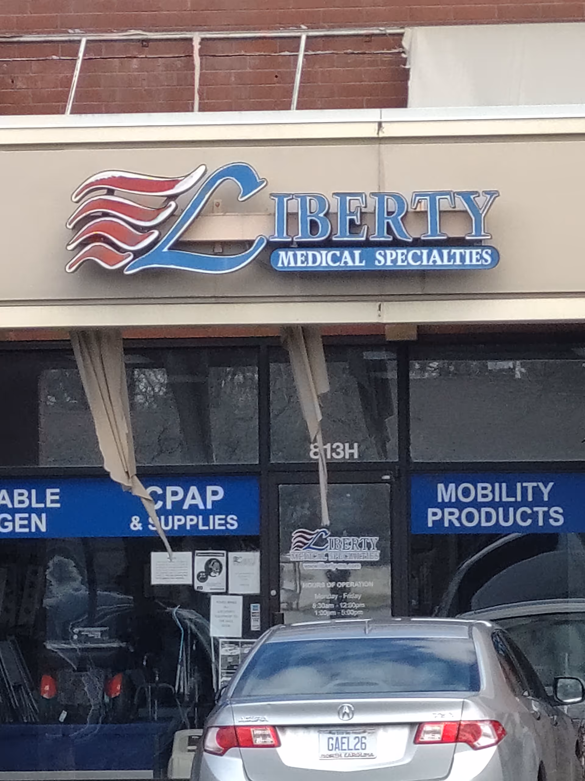 Exterior storefront of Liberty Medical Specialties with blue signage and a parked car in front.