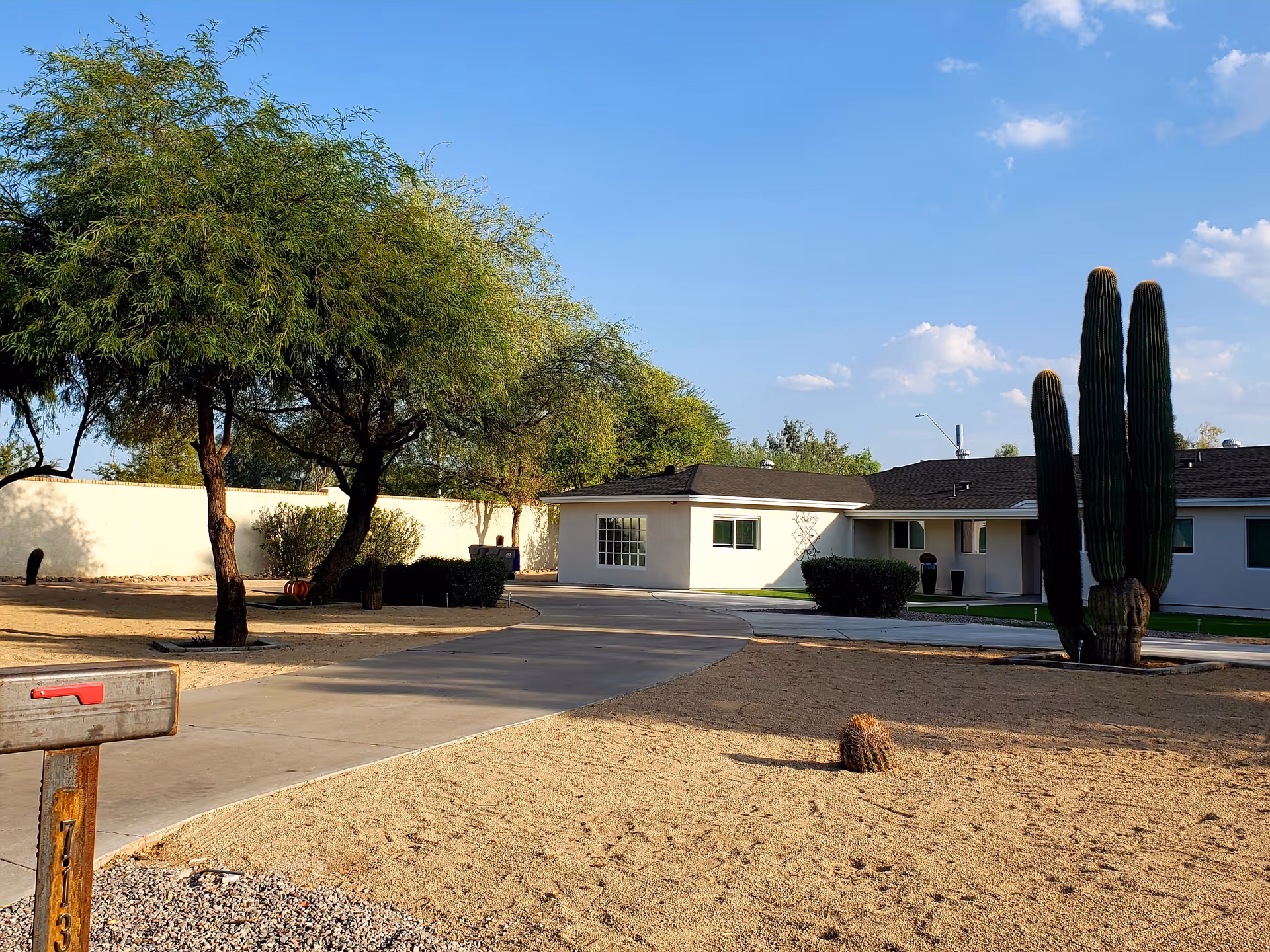 Front view of Sunrise Care Homes Paradise Valley with driveway, trees, and desert landscaping.