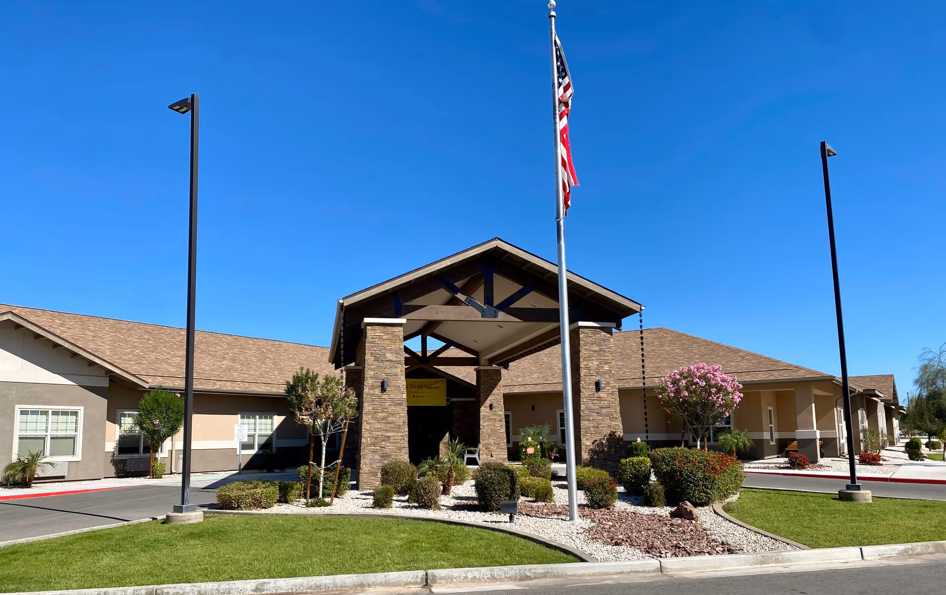 Front view of River Valley Estates senior living facility with entrance, flagpole, and landscaping.