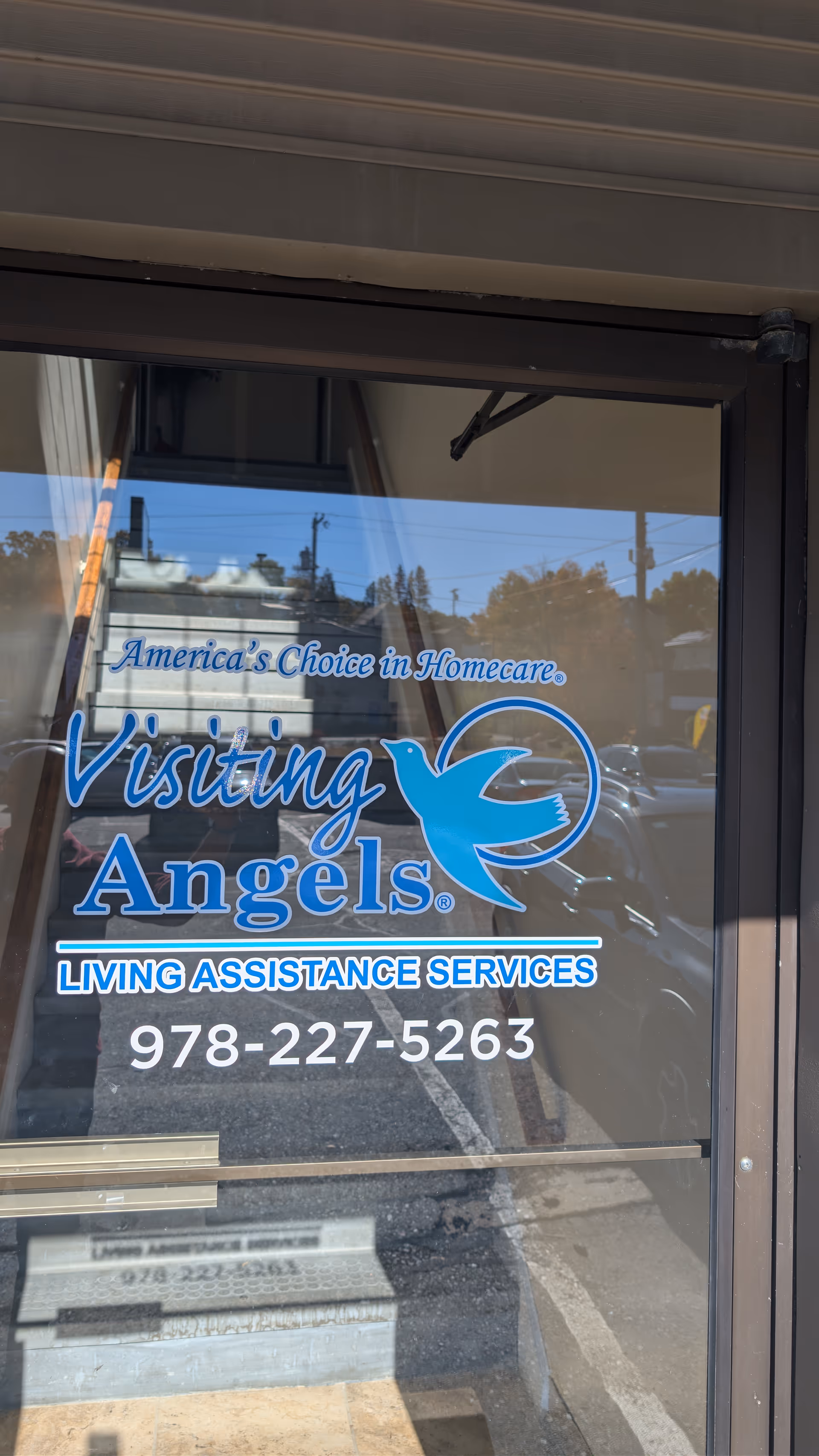Glass door with Visiting Angels sign and phone number at facility entrance.