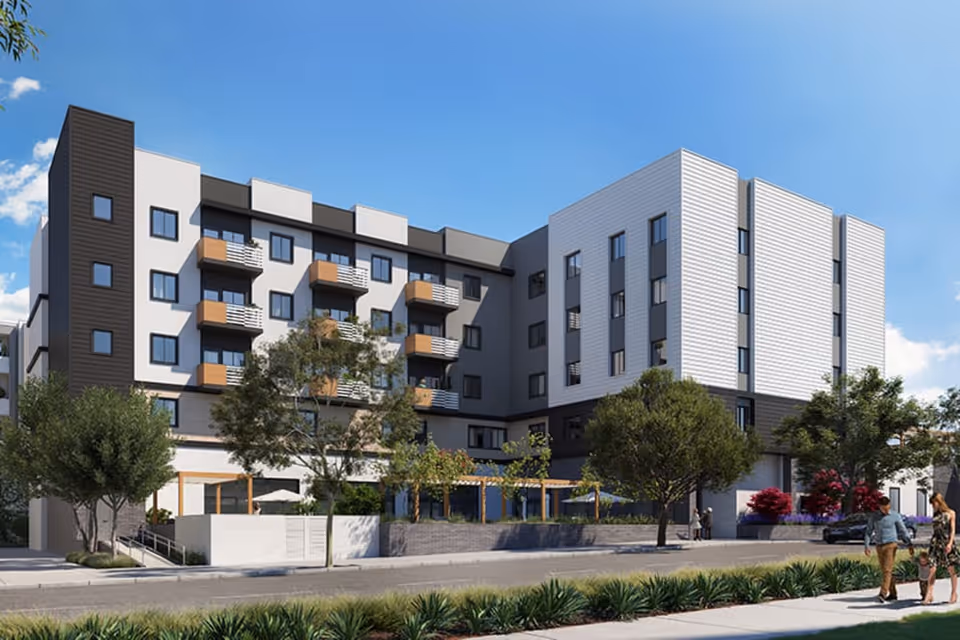 Modern multi-story senior living building with balconies, landscaping, and people walking on the sidewalk.