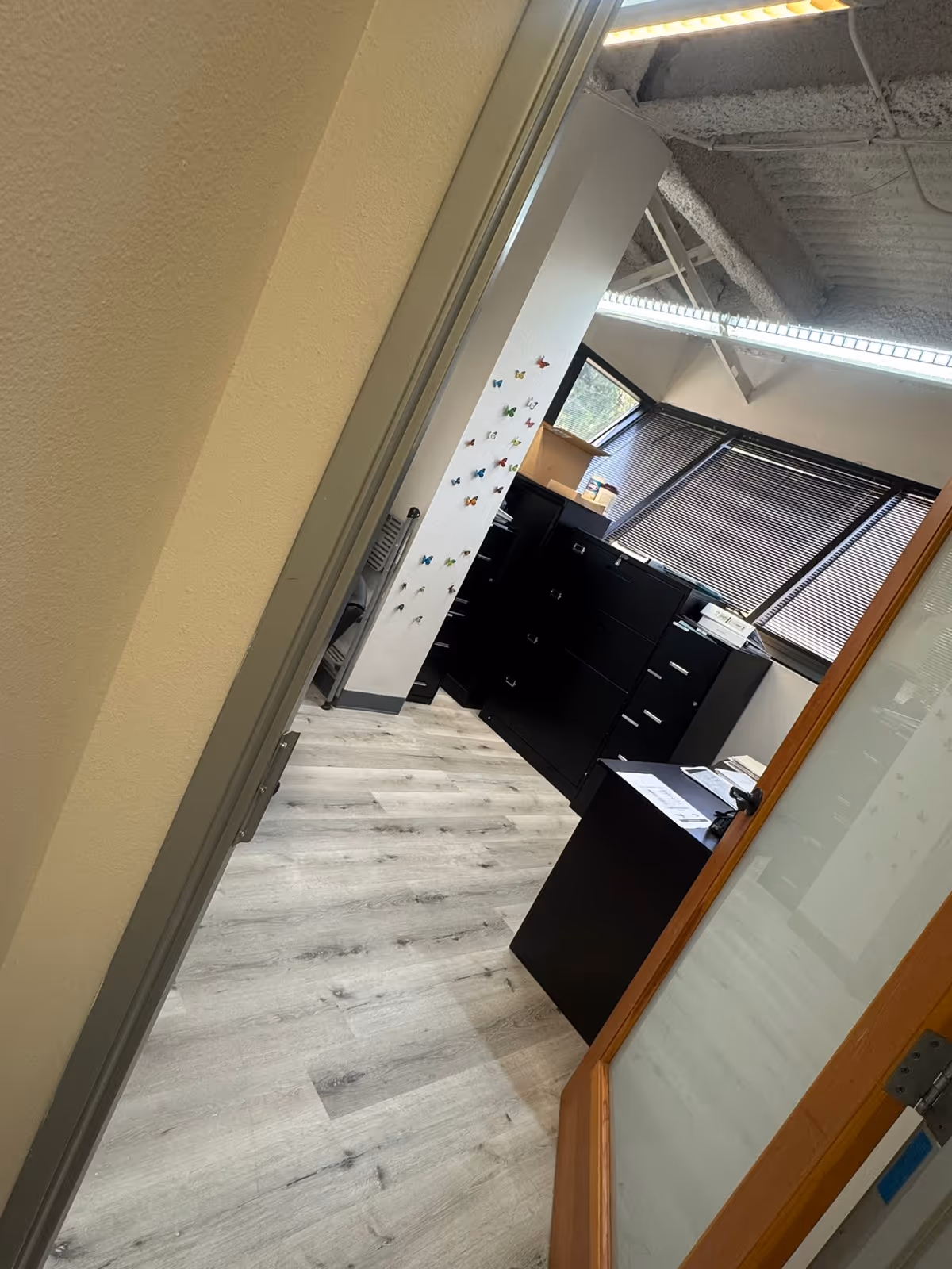 Interior office space with filing cabinets, butterfly decals, desk, and exposed ceiling.