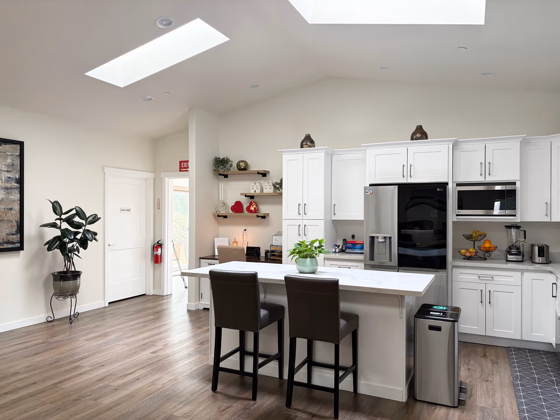 Bright modern kitchen with white cabinets, stainless appliances, and an island with two stools.