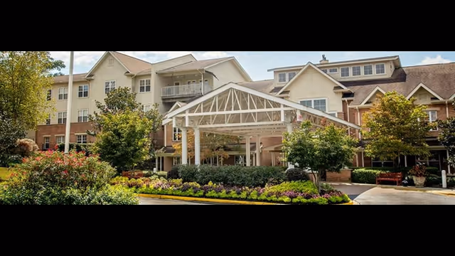 Front entrance of Town Village Vestavia Hills senior living building with a covered porte-cochère and landscaped gardens.