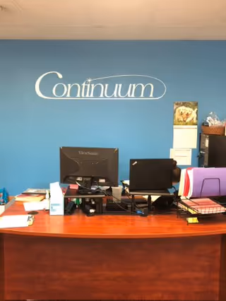 Reception desk with computers and office supplies against a blue wall with Continuum
