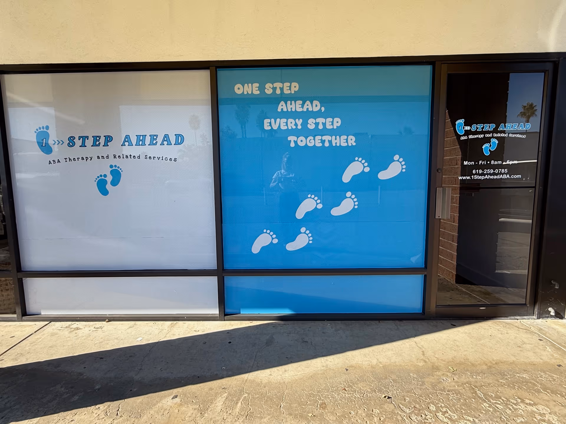 Storefront of 1-Step Ahead ABA with blue signage and footprint graphics.