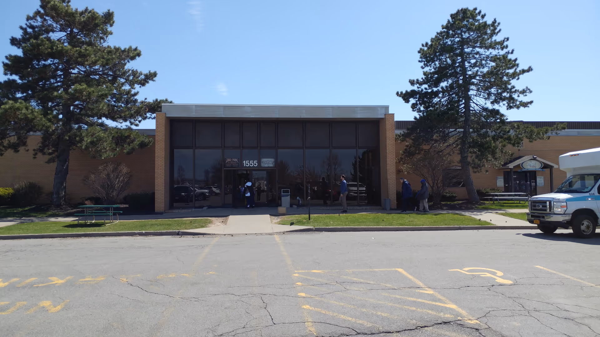 Exterior view of a senior living facility entrance with glass doors and surrounding trees.