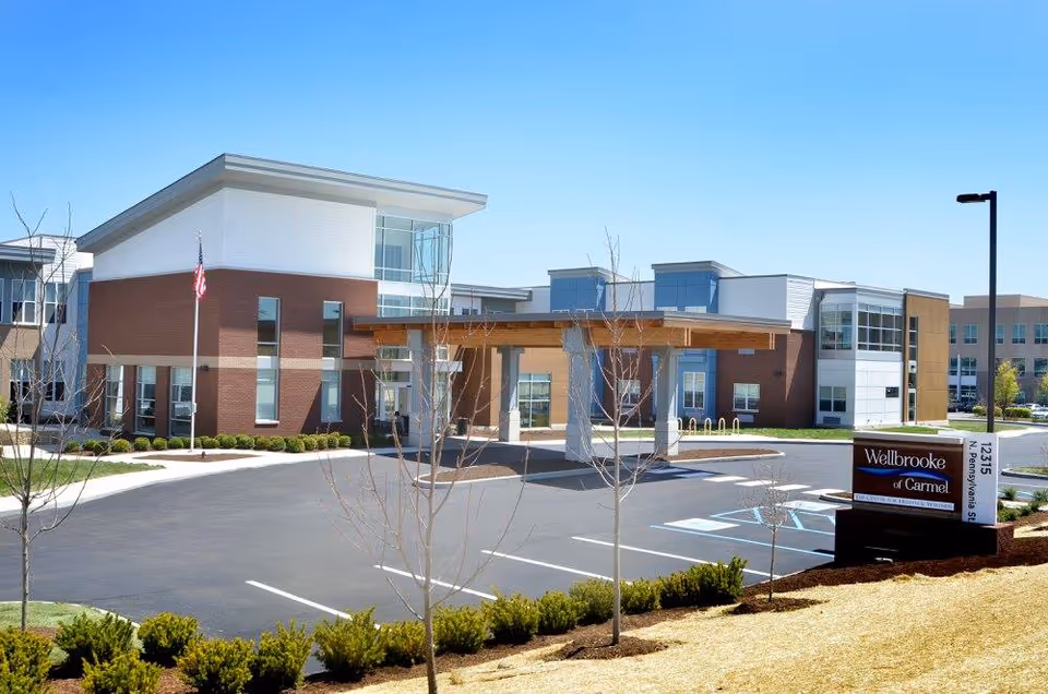 Wellbrooke of Carmel senior living facility exterior with driveway, entrance canopy, and sign.
