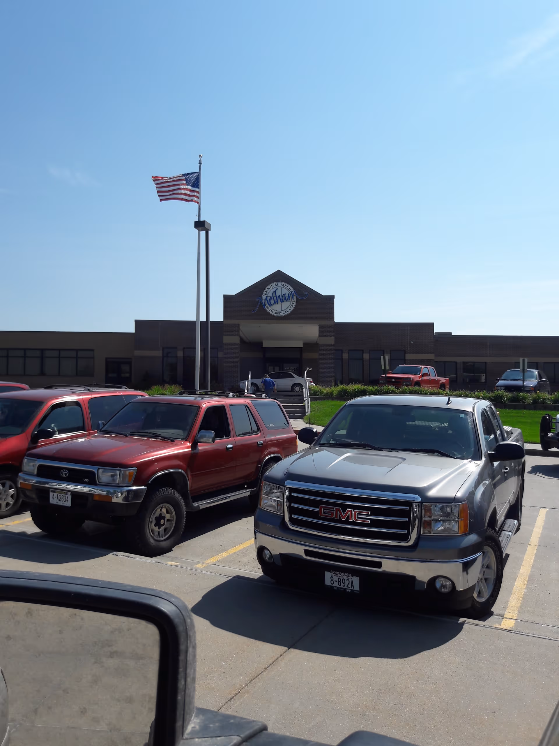 Front view of Jennie M. Melham Memorial Medical Center with parked cars in the lot.