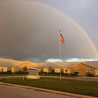 Exterior view of The Brixton at Horseshoe Bay with a rainbow over the building and flag.