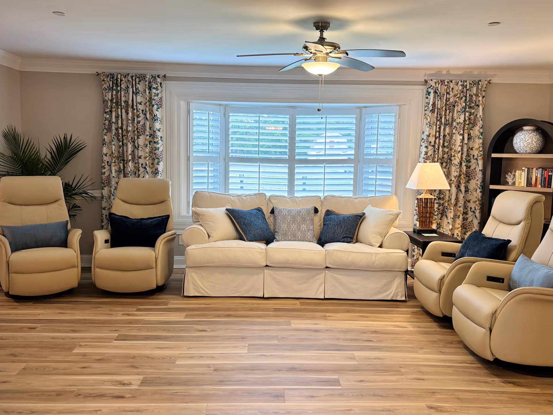 Cream seating area with a sofa and recliners in a bright living room.