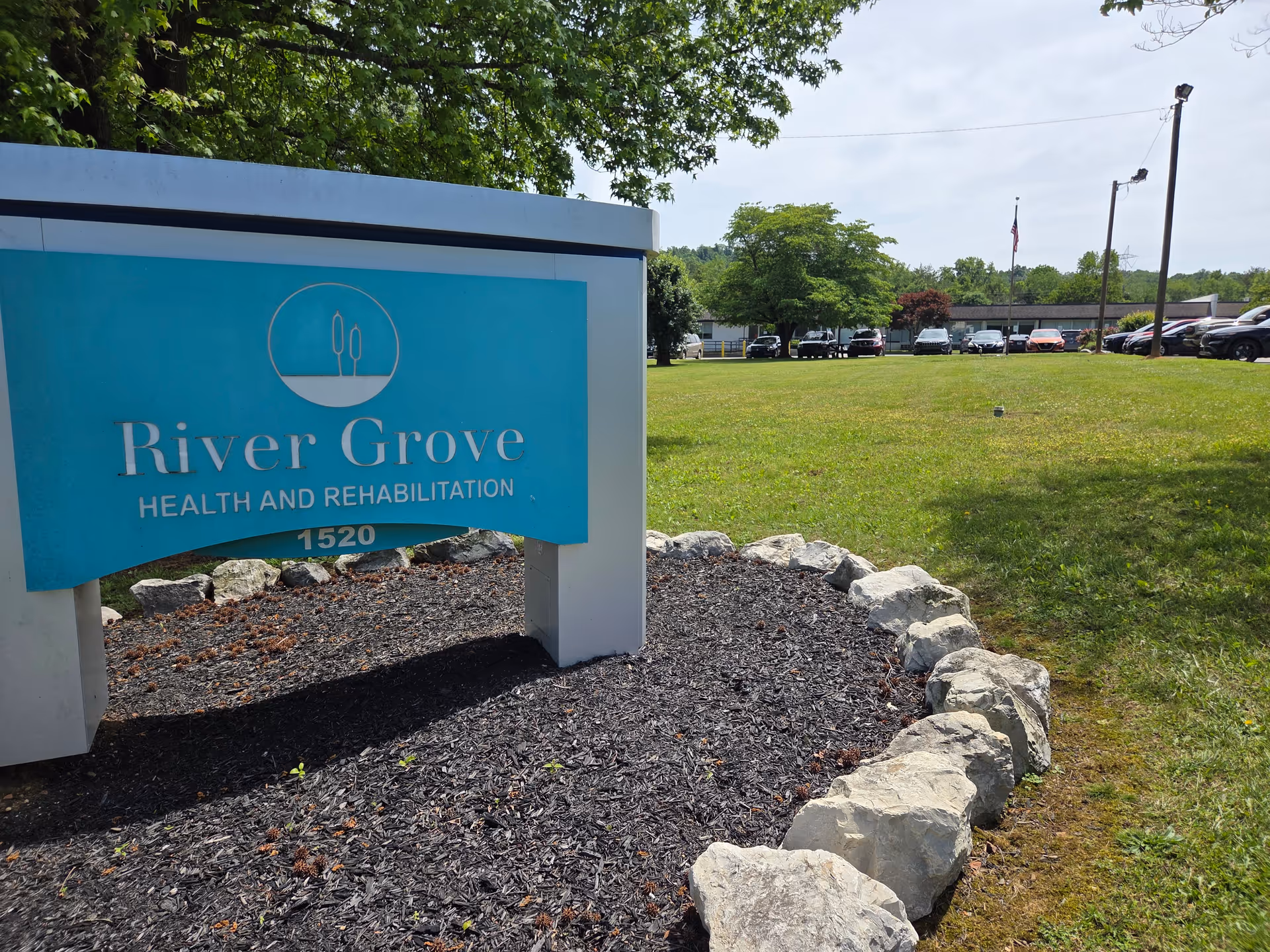 Sign for River Grove Health and Rehabilitation at a grassy front yard.