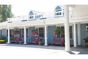 Exterior of Suffield House with a covered porch, rocking chairs and hanging baskets