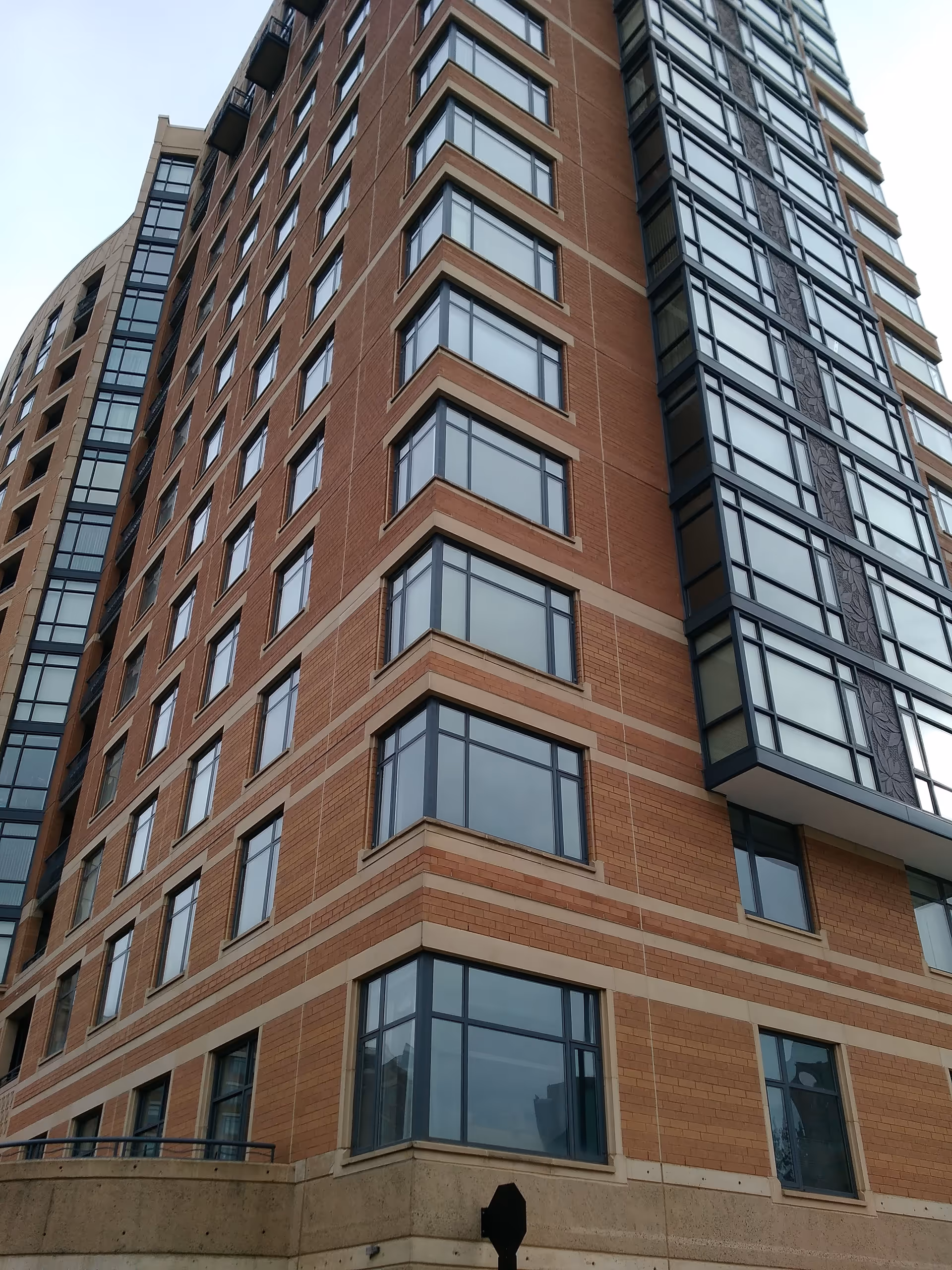 Tall brick senior living facility exterior features many large windows.